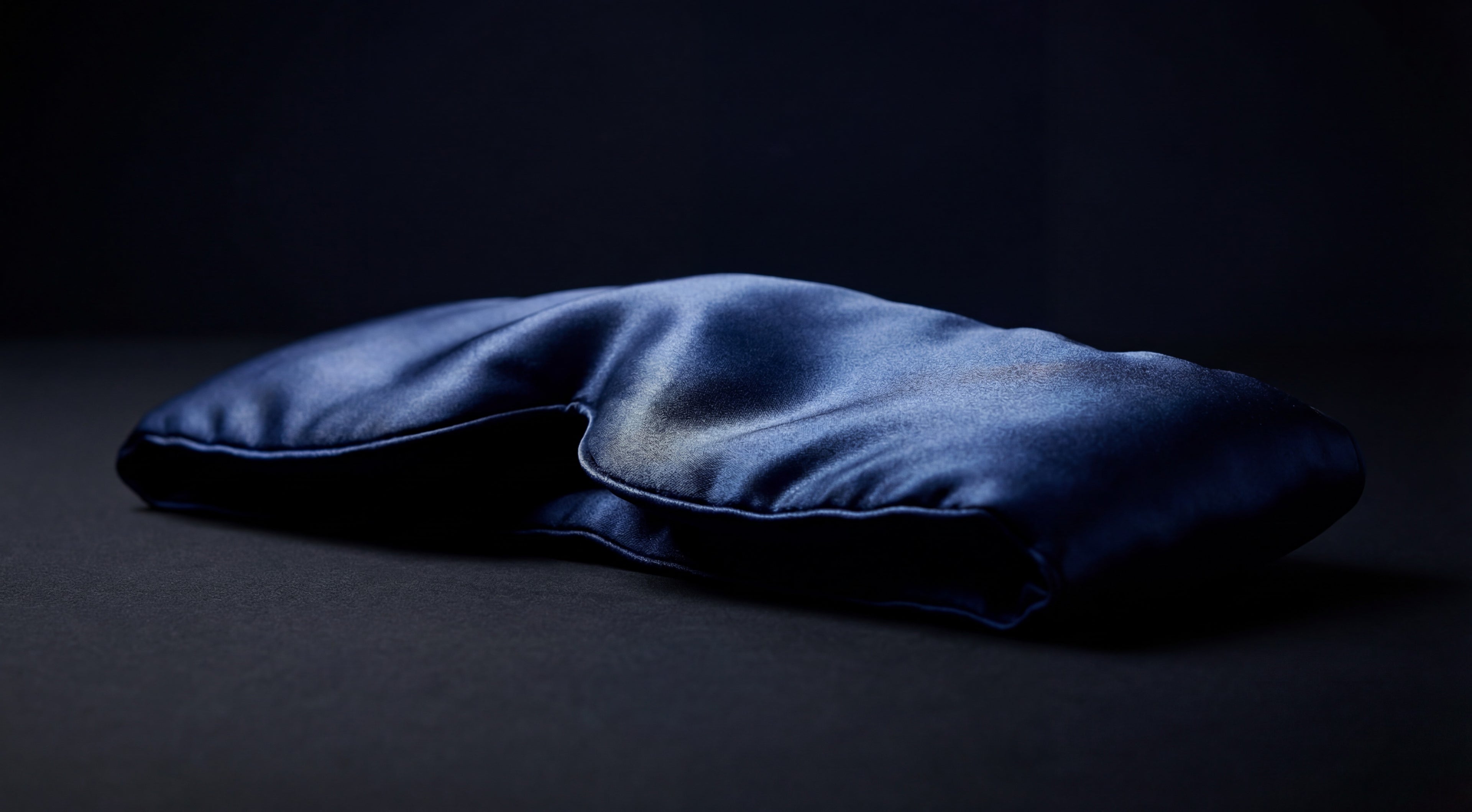 Blue U-shaped sleep mask on a dark background