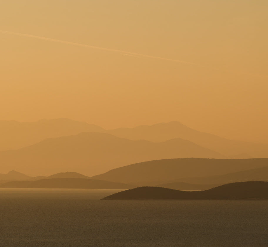 Hazy landscape with mountains and a gradient orange sky